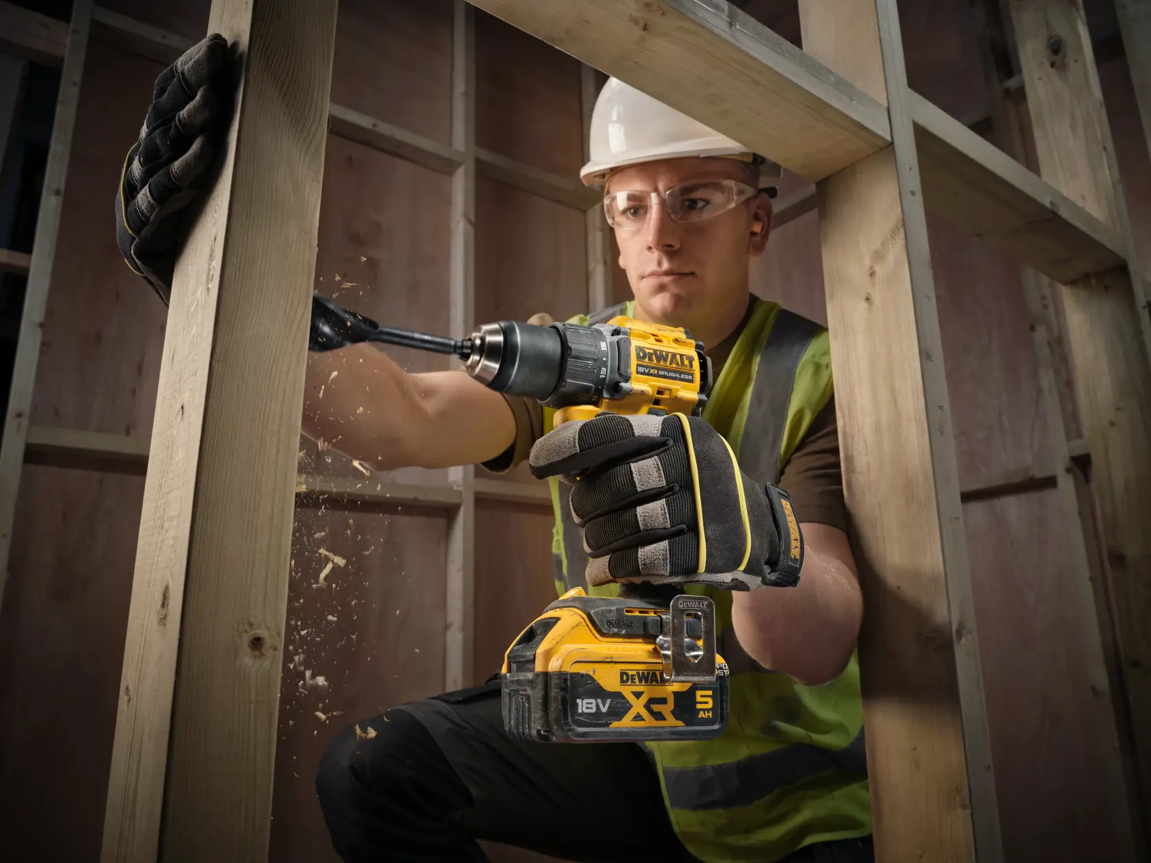 Worker drills wood using DEWALT DCD794NT, DCD794NT-XJ cordless tools. Construction setting.