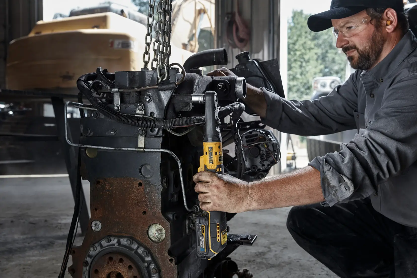 Persona usa una llave de carraca inalámbrica DEWALT en maquinaria en un taller industrial.