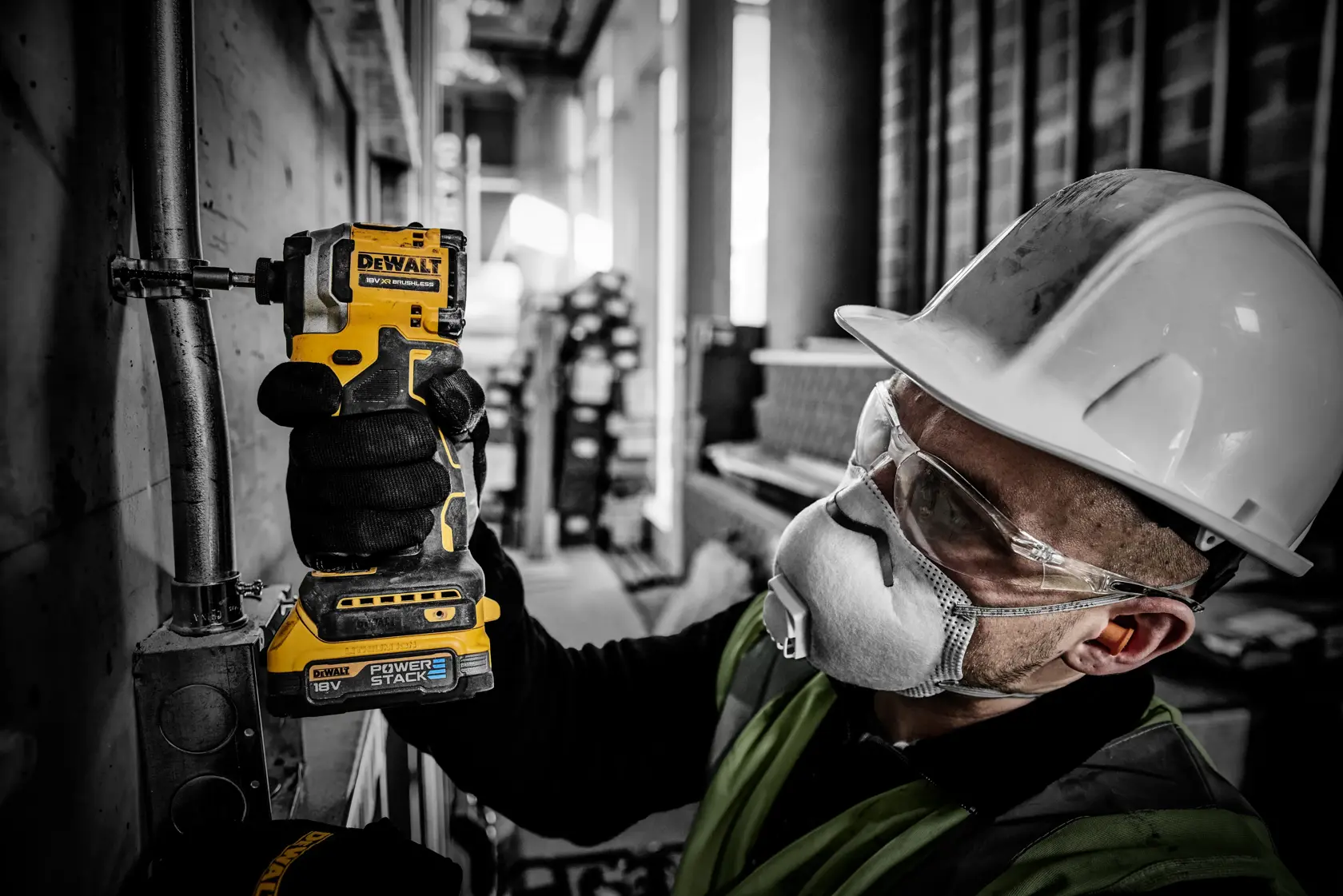 Lavoratore usa trapano DEWALT DCF850E2T su tubo, con casco e protezioni in un cantiere.