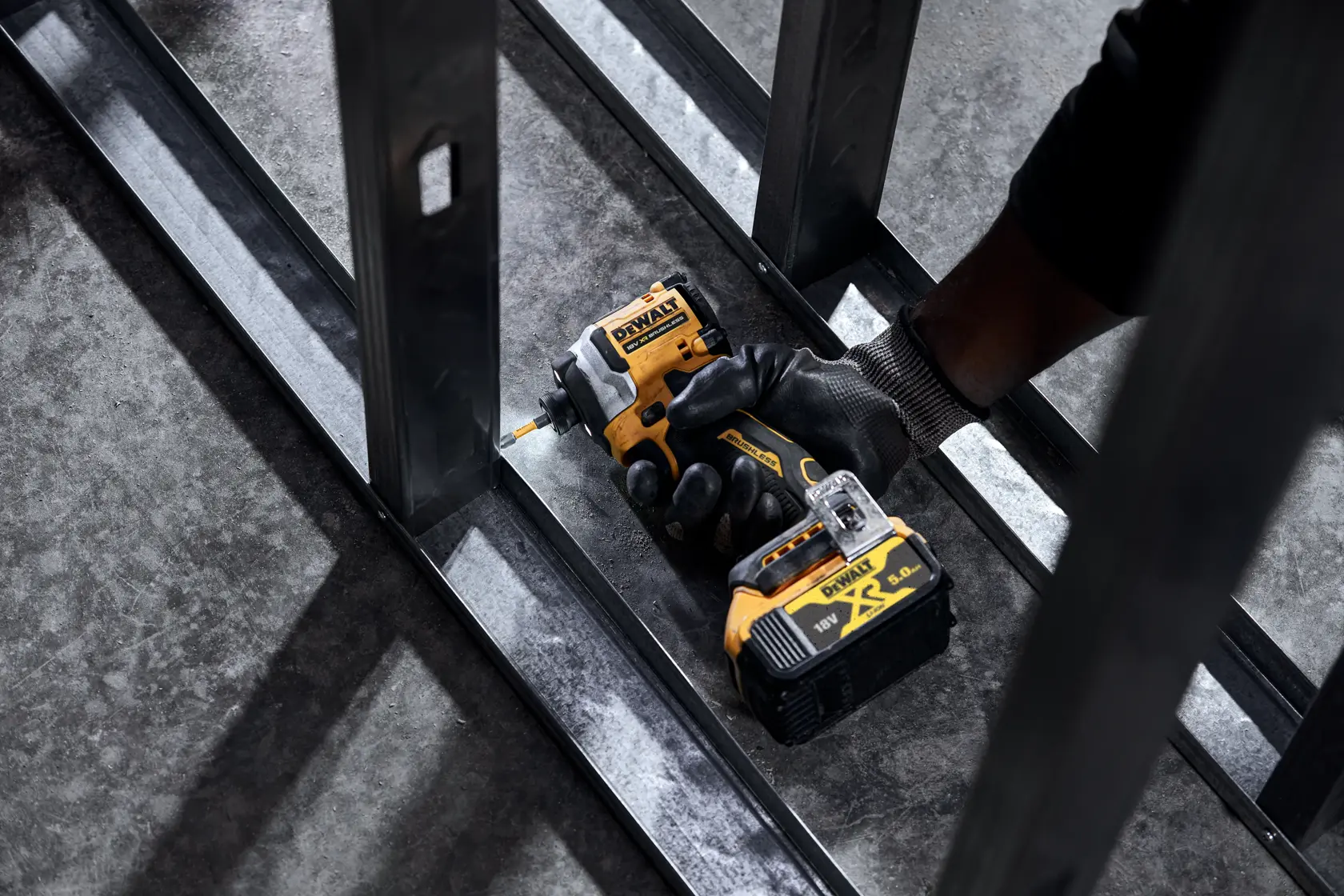 DEWALT DCF850N, DCZ2050P2T-XE, DCZ401P3-XE impact driver held by gloved hand working on metal structure.