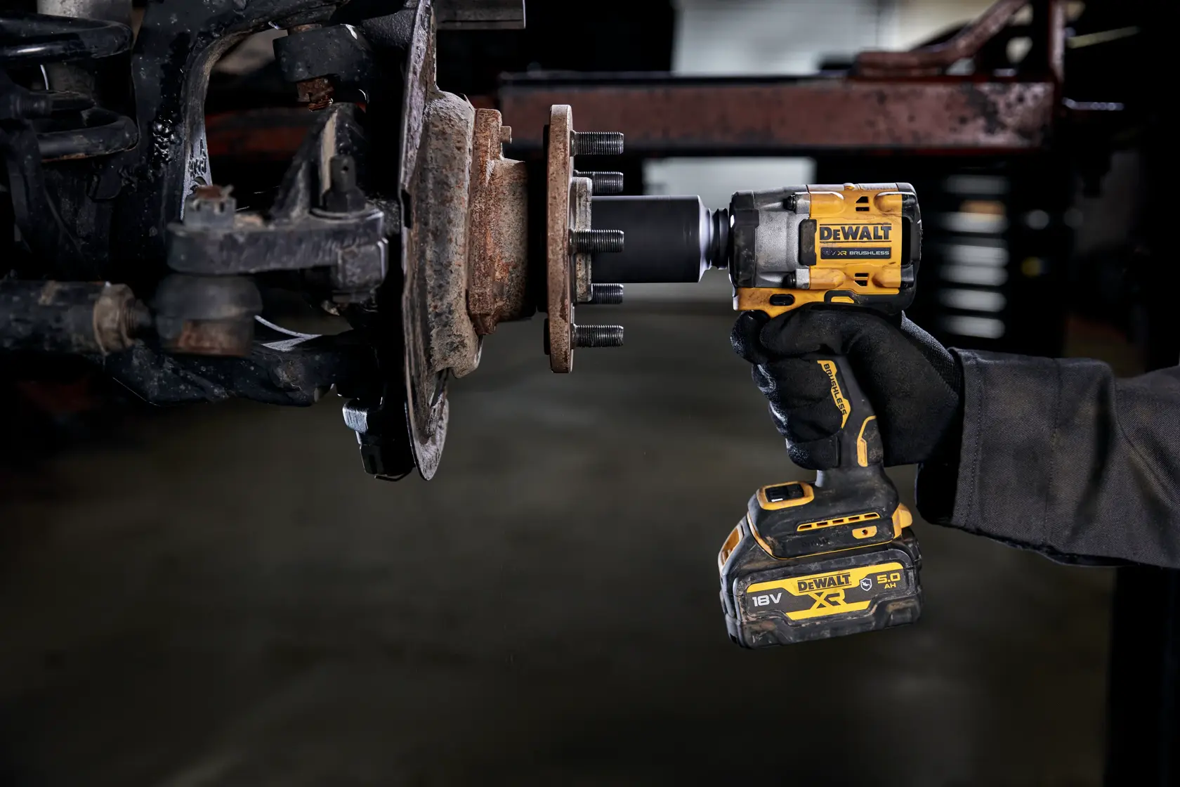 Eine Person verwendet einen kabellosen DEWALT-Schlagschrauber (Modell DCF921P2G), um Radmuttern an einer Radnabe eines Fahrzeugs zu lösen oder anzuziehen.