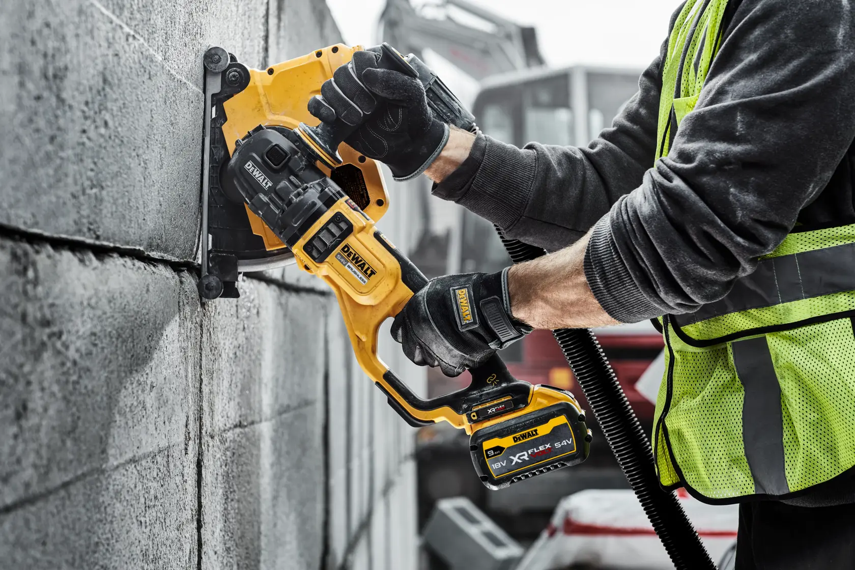 Person verwendet DEWALT Akku-Wandschlitzer für Fugen in Betonsteinen auf Baustelle.