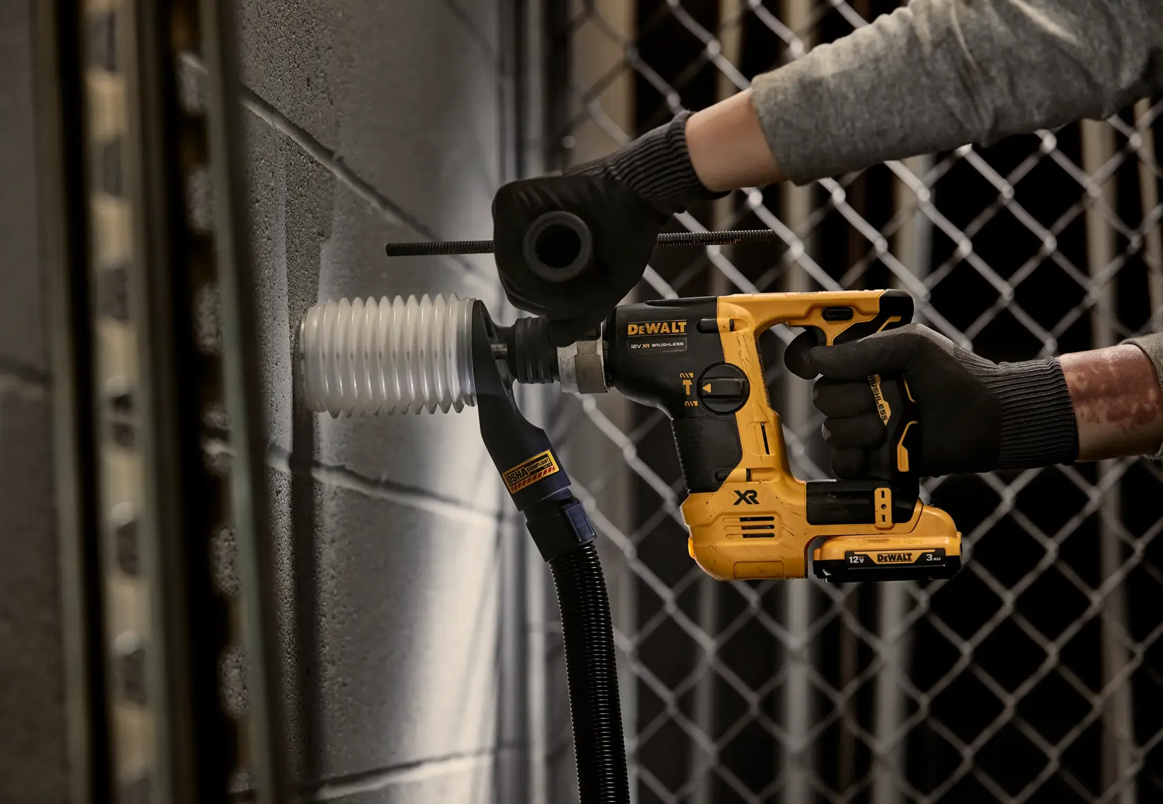 Perforateur sans fil DEWALT perce un mur en béton avec un accessoire d’extraction de poussière.