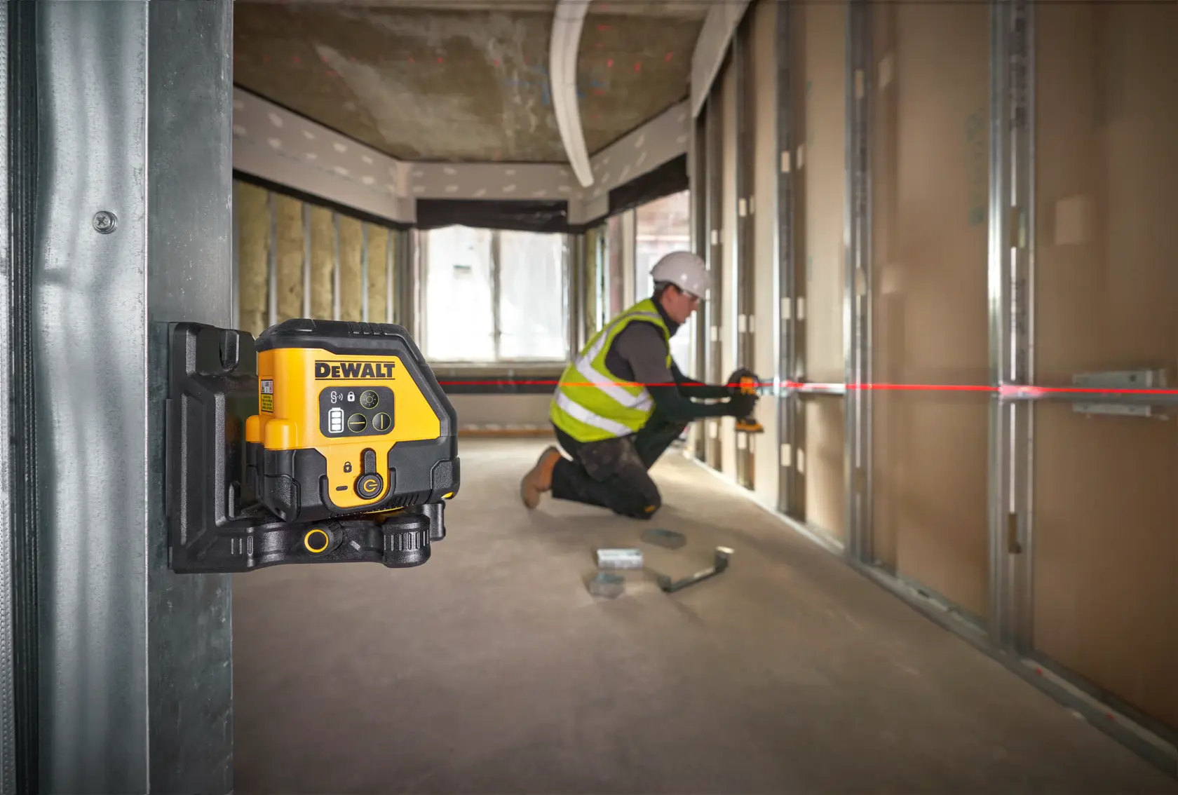 Livella laser DEWALT installata, operaio allinea struttura metallica con linea laser rossa.