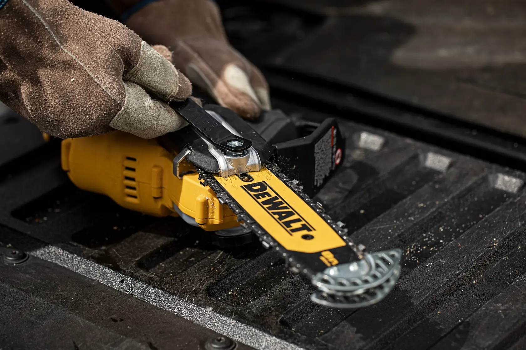 Manos con guantes ajustan sierra DEWALT DCMPS520P1 sobre superficie oscura.