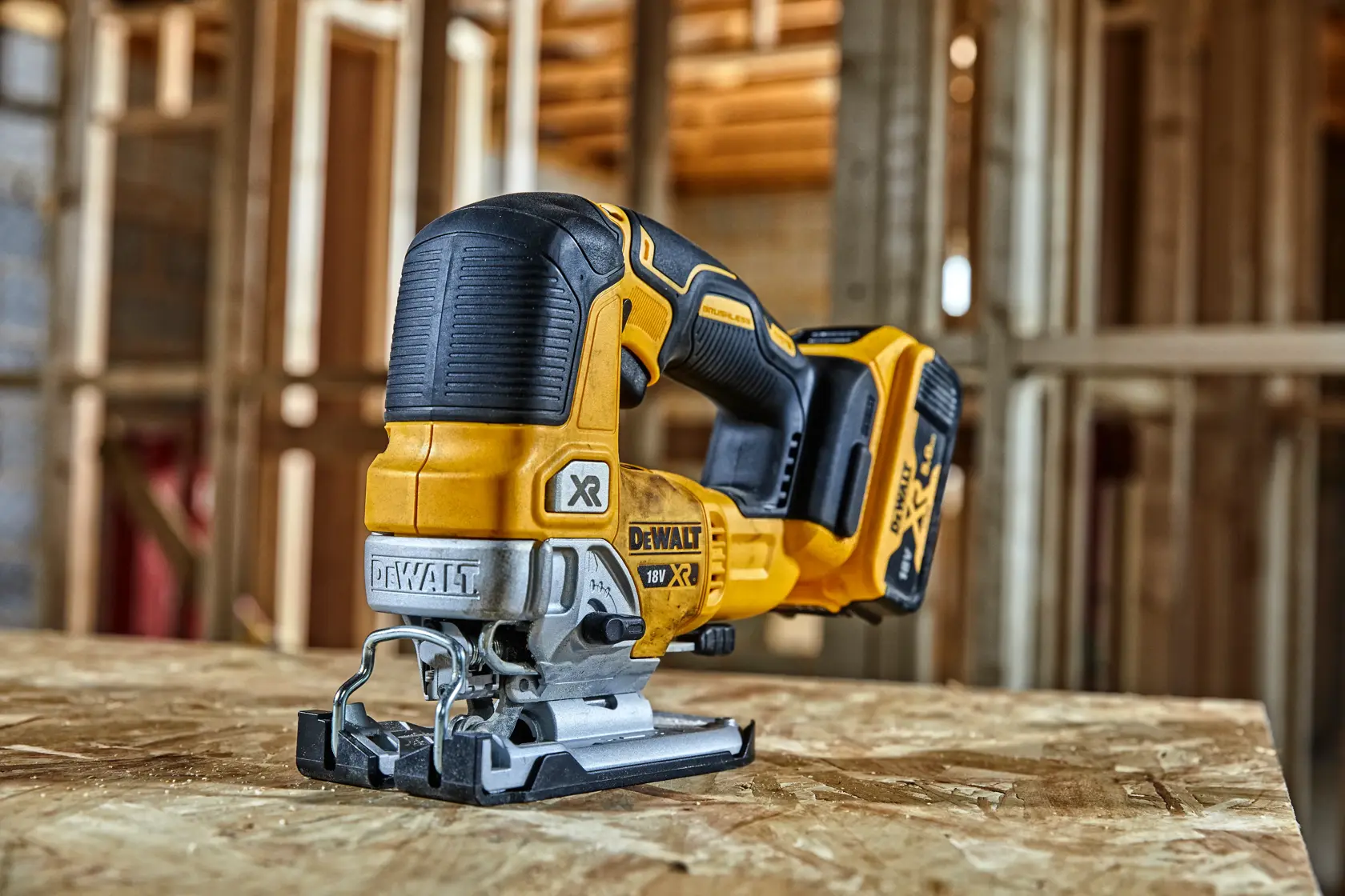 Sierra de calar inalámbrica DEWALT sobre madera contrachapada en obra, estructura de madera al fondo.