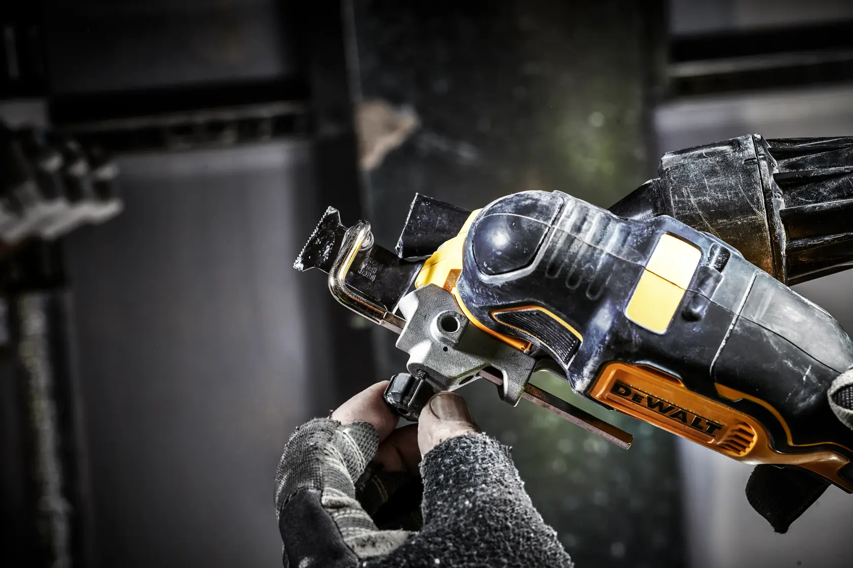 Mano con guante ajusta una multiherramienta oscilante DEWALT inalámbrica para cortar o lijar.