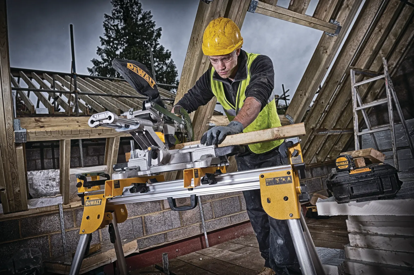 Arbeiter sägt Holz mit DEWALT DCS365N auf Baustelle, Holzrahmenbau und Schutzausrüstung sichtbar.
