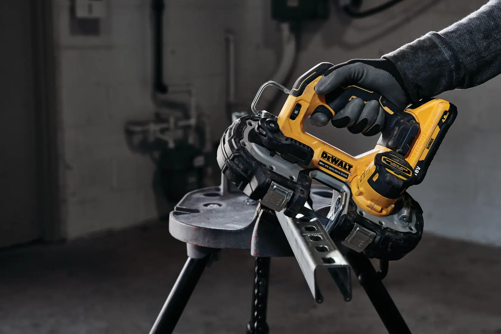 Scie à ruban sans fil DEWALT coupant du métal, utilisée par une main gantée en atelier.
