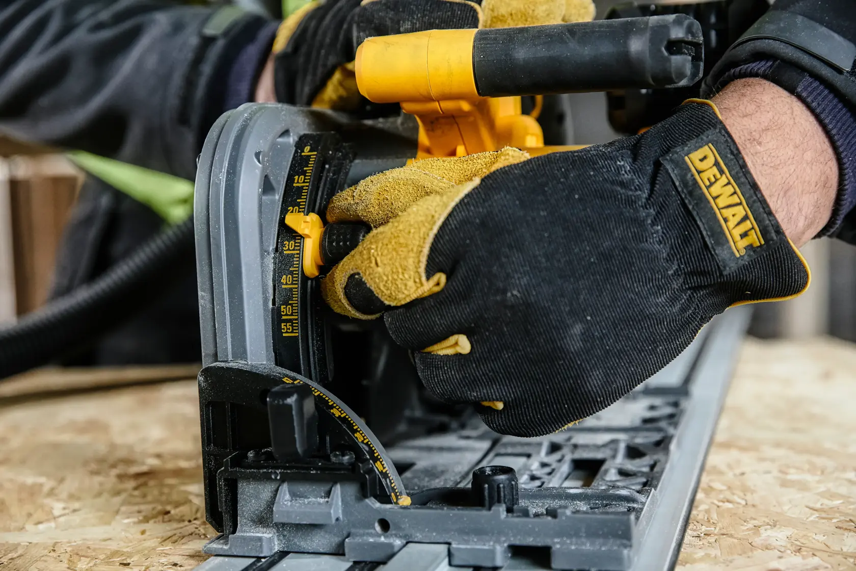 Behandschuhte Hände justieren den Winkel einer DEWALT Kreissäge auf Sperrholz. Nahaufnahme.