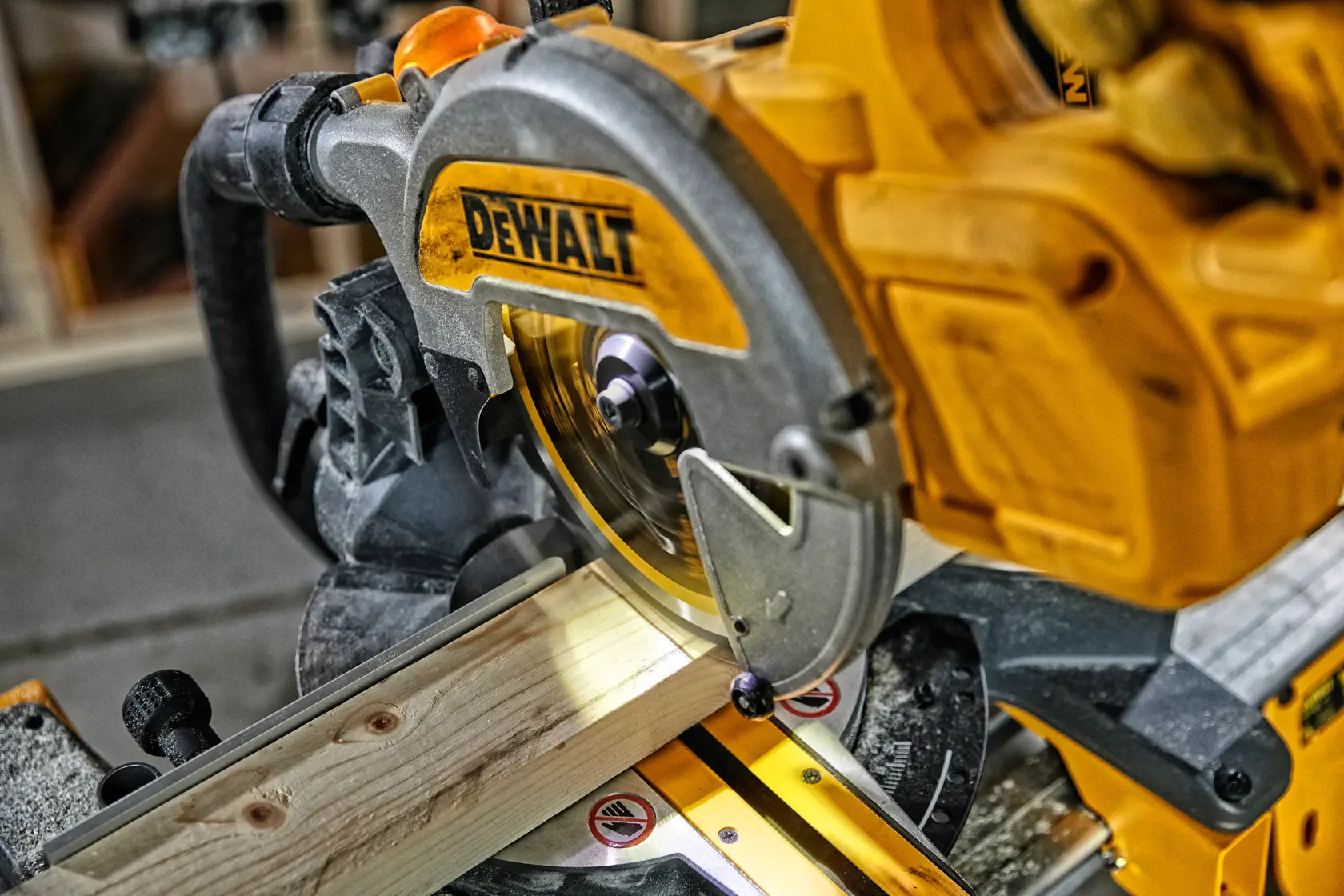 DEWALT miter saw cutting a piece of wood in a workshop. Close-up of the power tool in use.