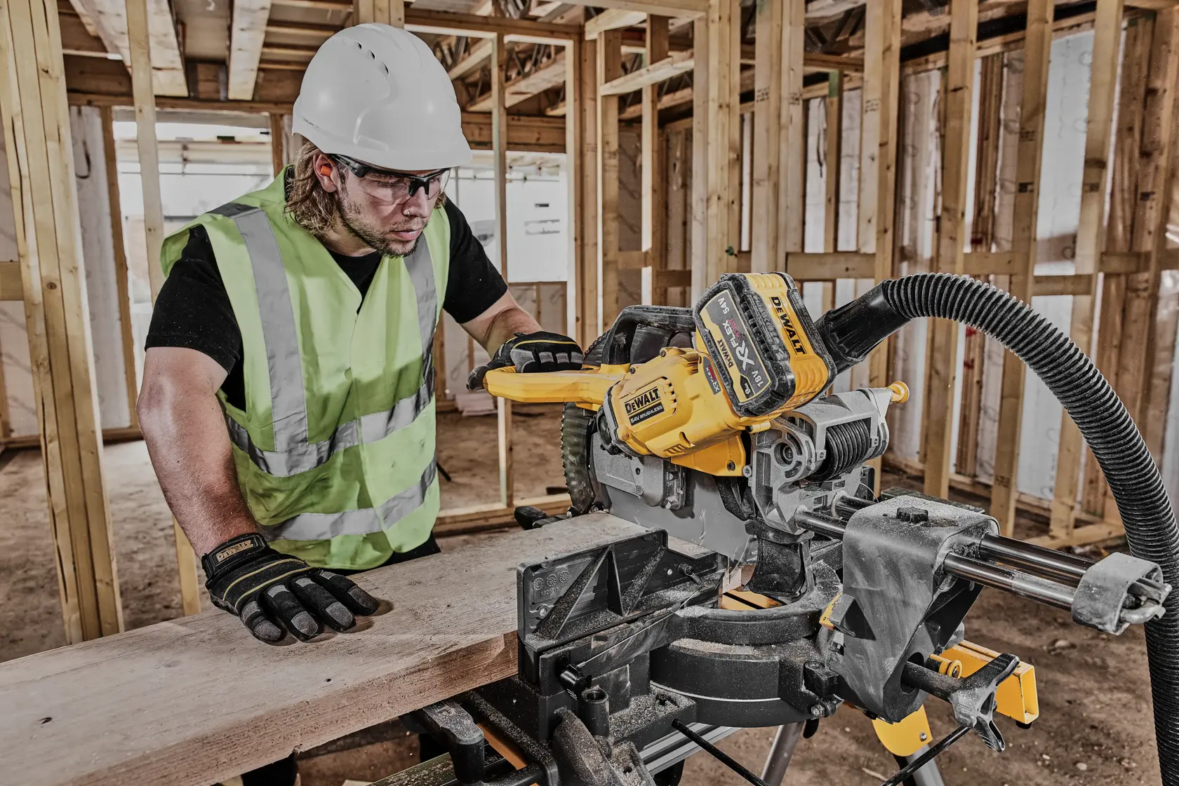 Arbeiter nutzt DEWALT DCS781N Säge für Holzschnitt auf Baustelle. Schutzkleidung und Warnweste getragen.