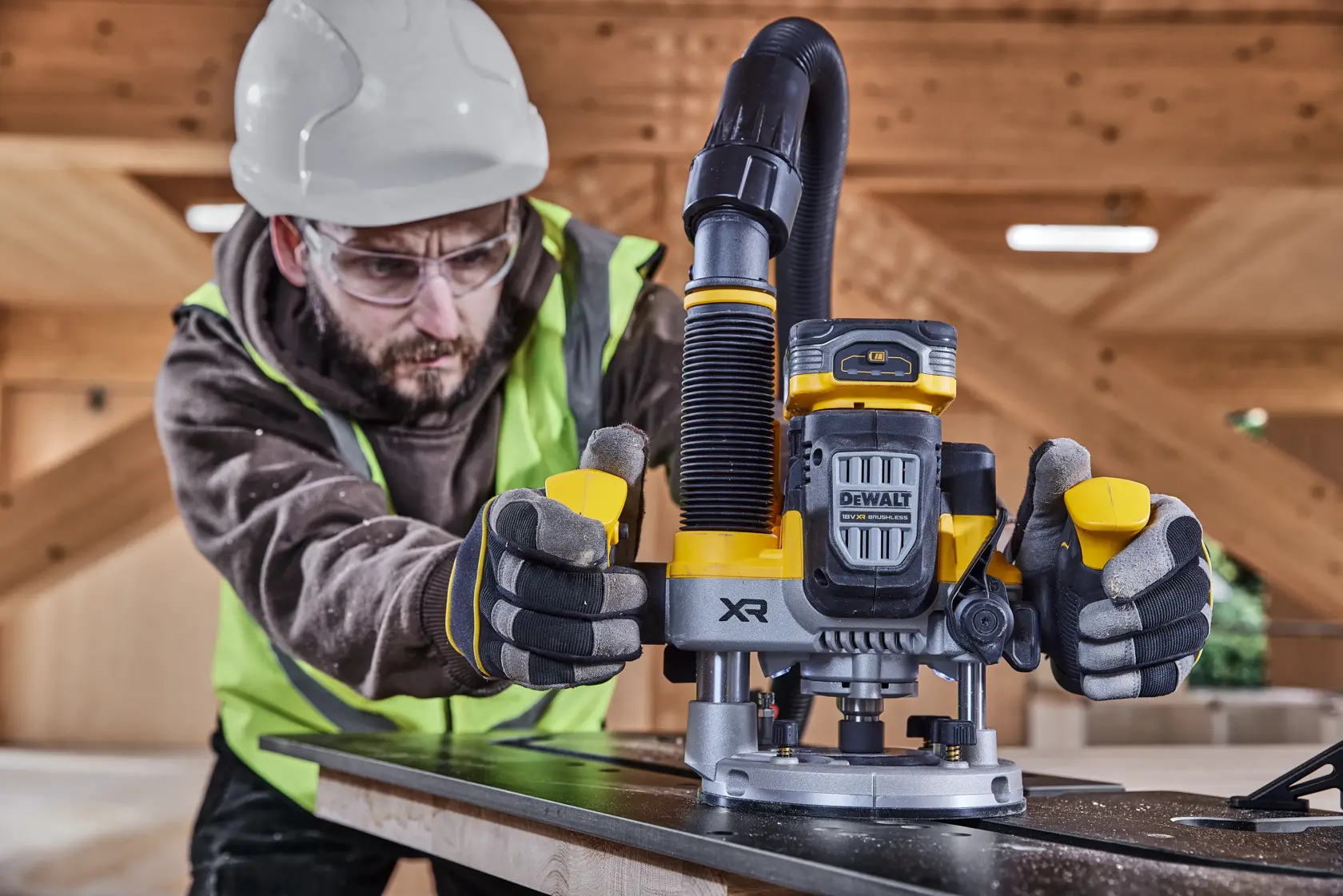 Arbeiter nutzt DEWALT XR DCW620H2 Akku-Fräse für Holz, mit Sicherheitsausrüstung im Bau.