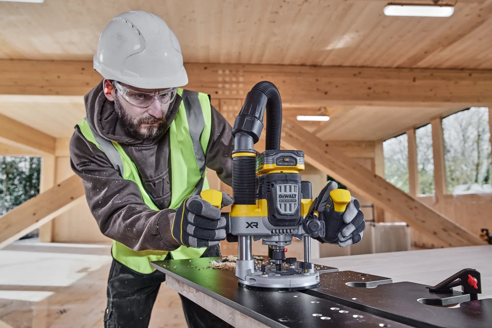 Trabajador usa DEWALT XR DCW620NT en metal, taller de madera, usando equipo de seguridad.