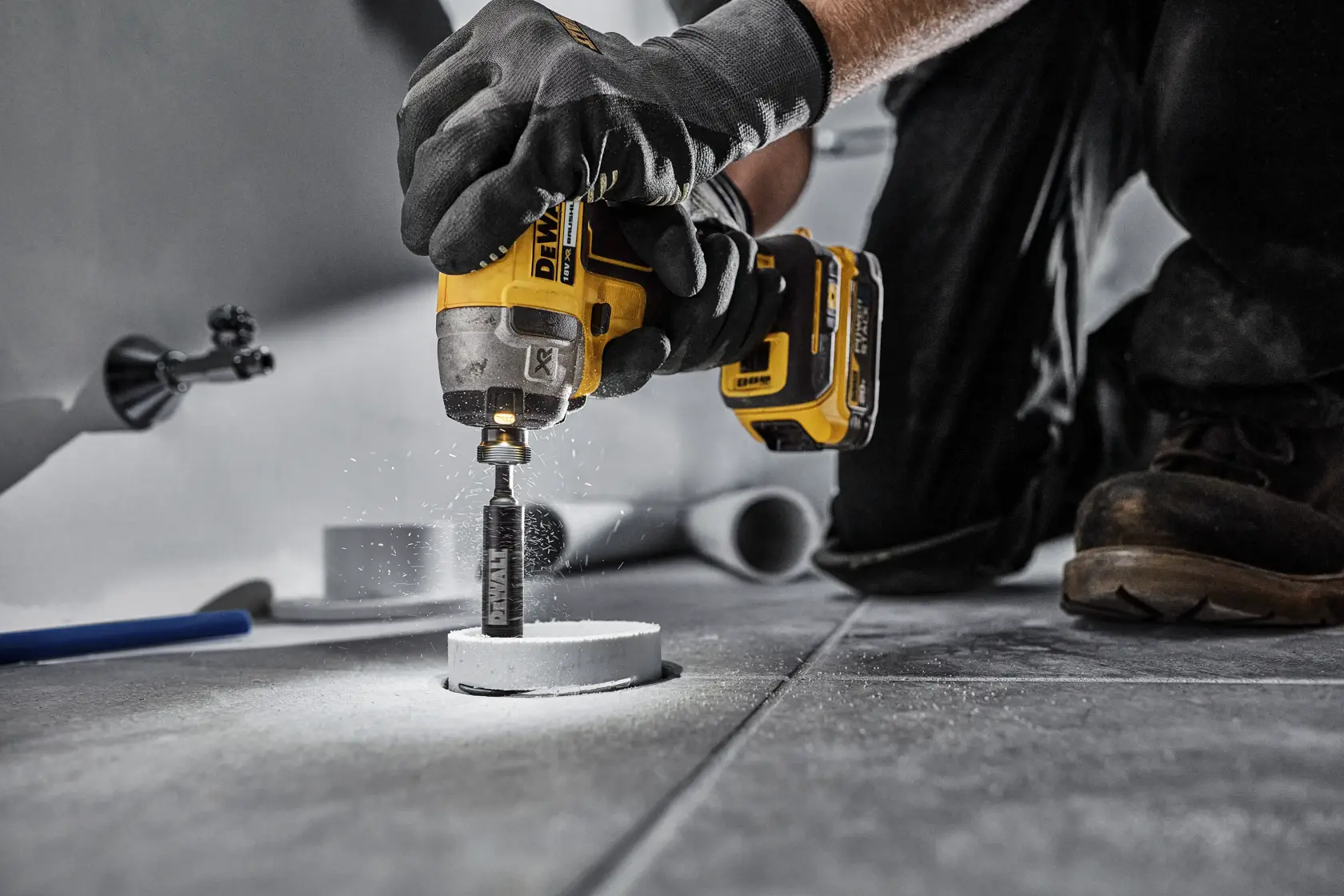 DEWALT DT20563 drill in use, drilling a hole in a tile floor. Worker wears gloves for safety.