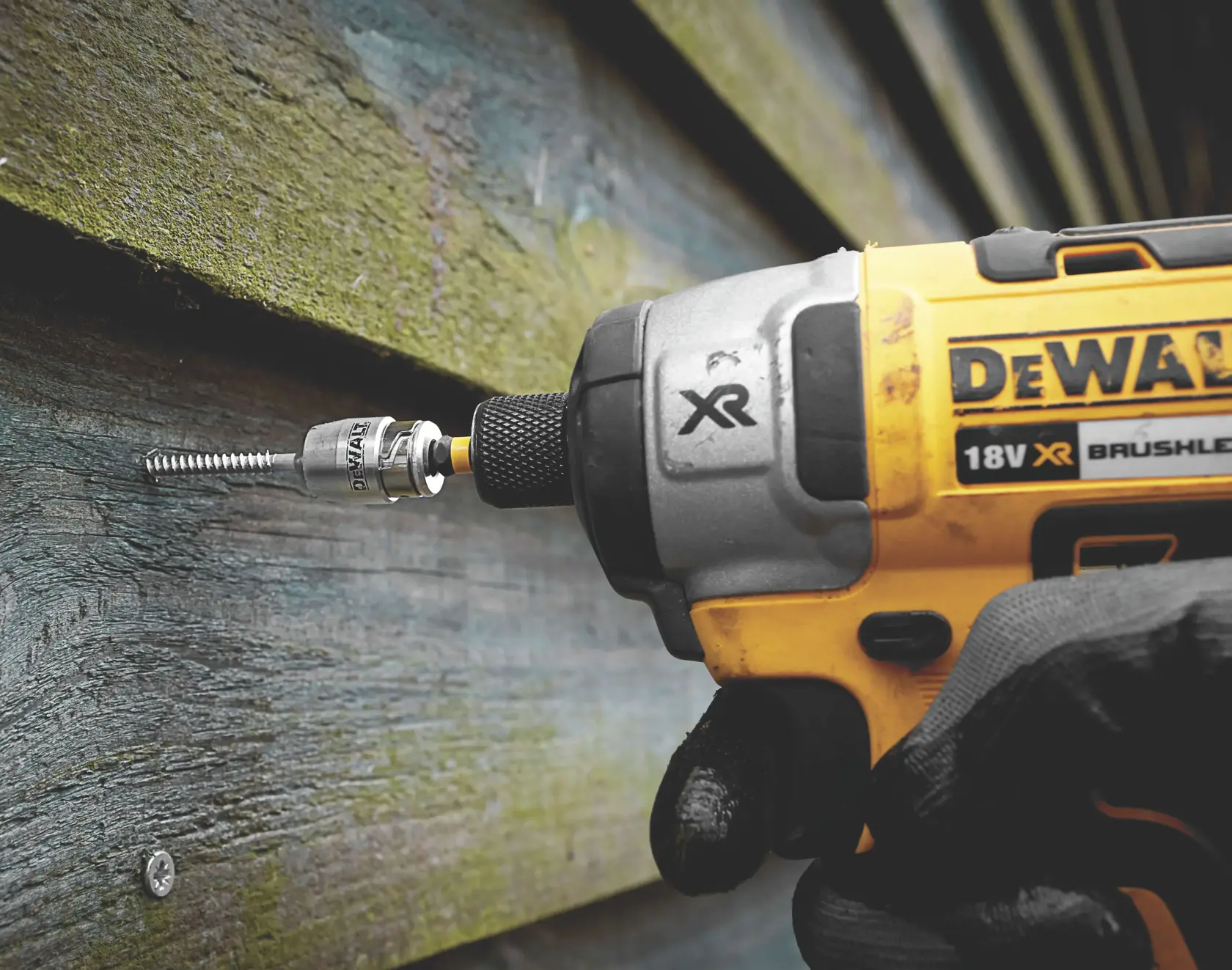 Taladro DEWALT inalámbrico atornillando en madera, primer plano de la herramienta y guante.