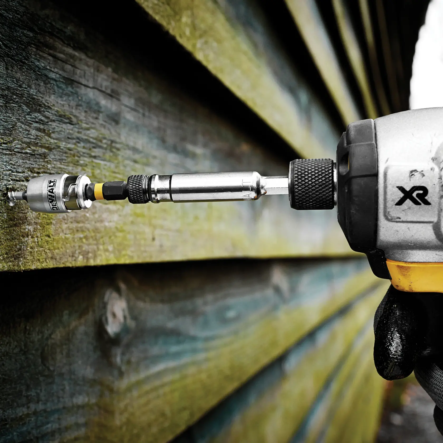 Taladro DEWALT con accesorio DT70537T atornilla en madera al exterior.