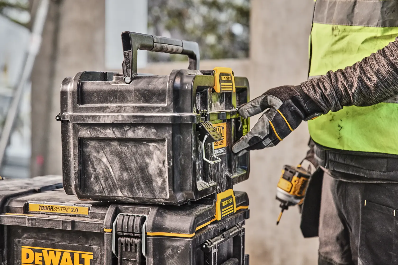 Mit Handschuh wird DEWALT Toughsystem 2.0 Werkzeugkasten am Arbeitsplatz geöffnet.